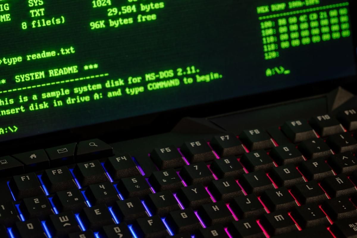 Écran affichant du code système et clavier gaming rétroéclairé en couleurs vives