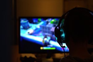 Une personne en silhouette porte un casque et regarde un écran de jeu vidéo