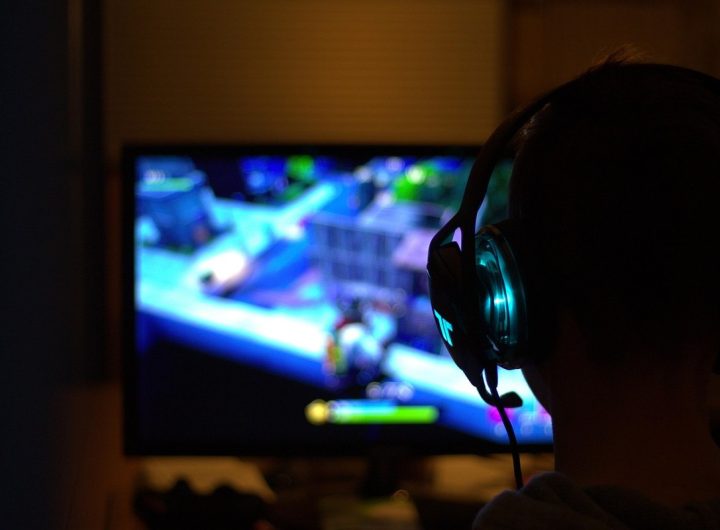 Une personne en silhouette porte un casque et regarde un écran de jeu vidéo