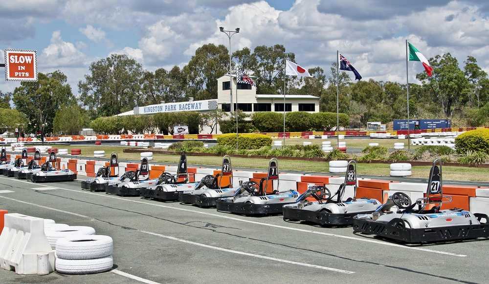 Piste de karting avec plusieurs karts orange et blancs stationnés le long de la barrière Piste de karting avec plusieurs karts orange et blancs stationnés le long de la barrière