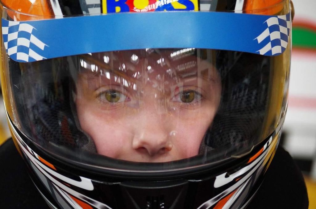 Enfant équipé d'un casque de karting bleu blanc noir avec visière teintée