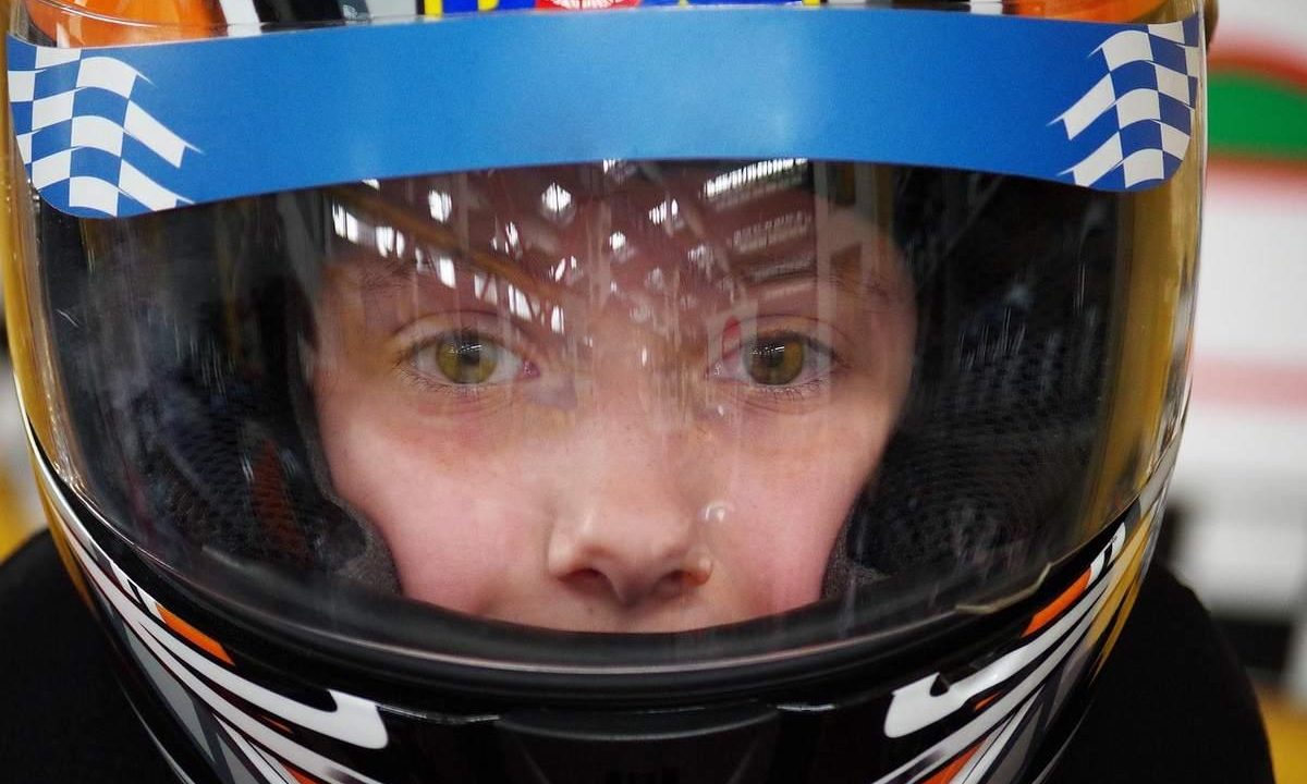 Enfant équipé d'un casque de karting bleu blanc noir avec visière teintée