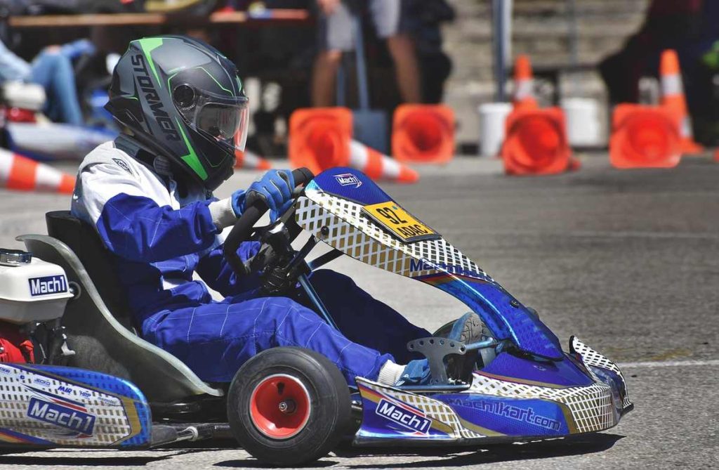 Un conducteur en kart bleu pilote sur circuit avec cônes orange