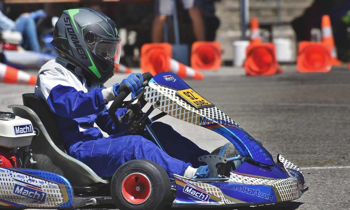 Un conducteur en kart bleu pilote sur circuit avec cônes orange