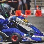 Un conducteur en kart bleu pilote sur circuit avec cônes orange