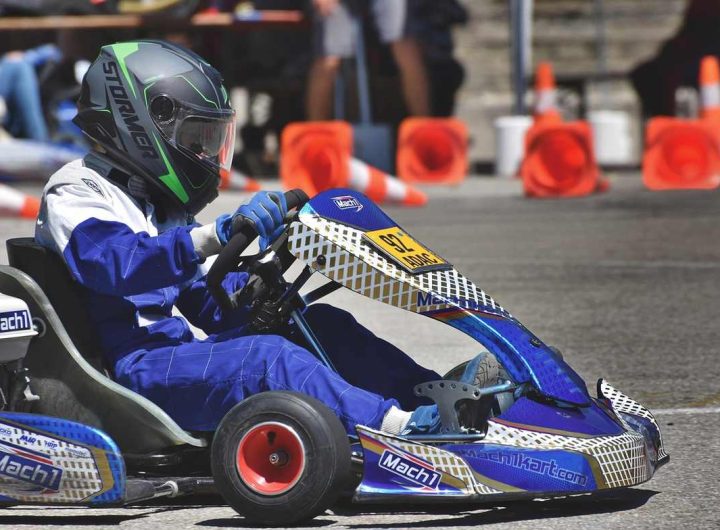 Un conducteur en kart bleu pilote sur circuit avec cônes orange
