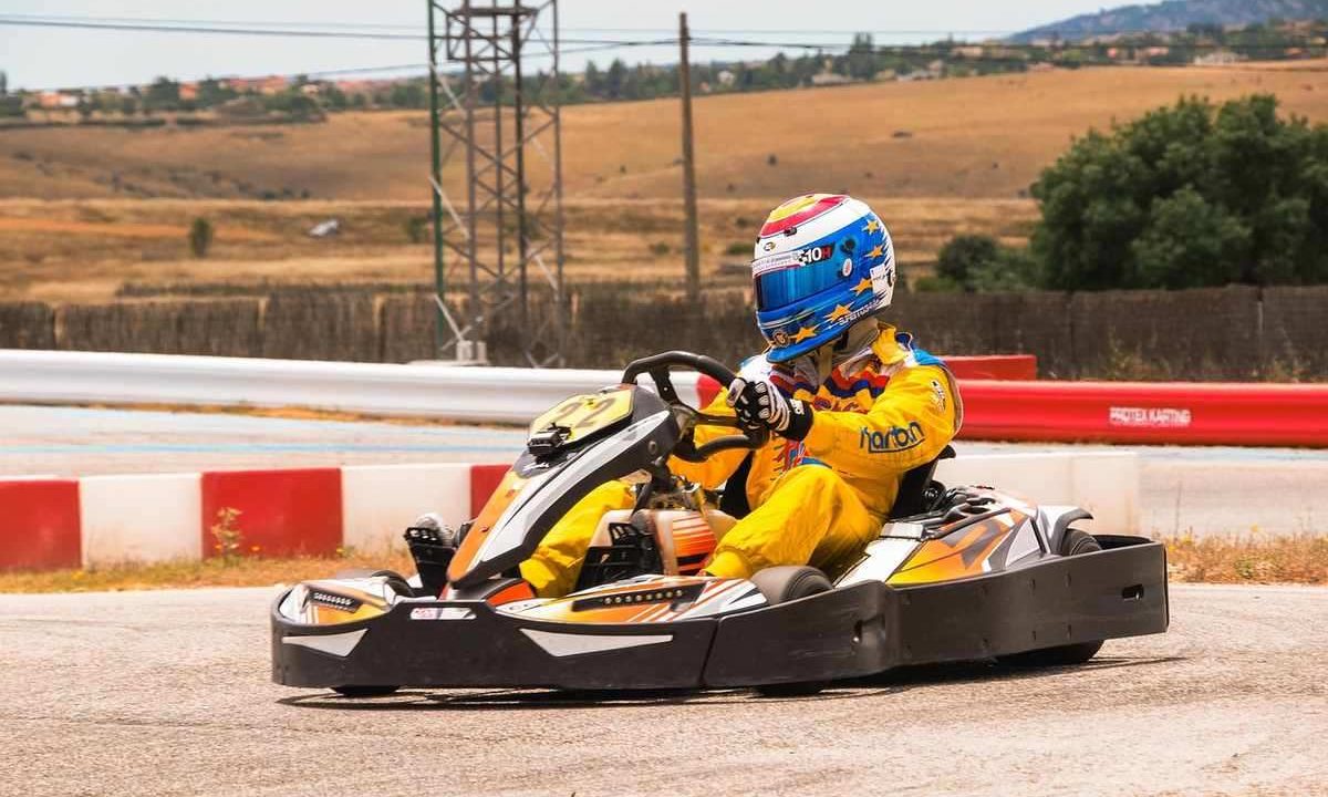 Pilote vêtu d'une combinaison jaune conduisant un kart sur une piste avec barrières rouges et blanches