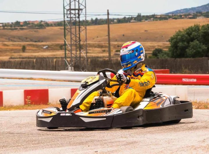 Pilote vêtu d'une combinaison jaune conduisant un kart sur une piste avec barrières rouges et blanches