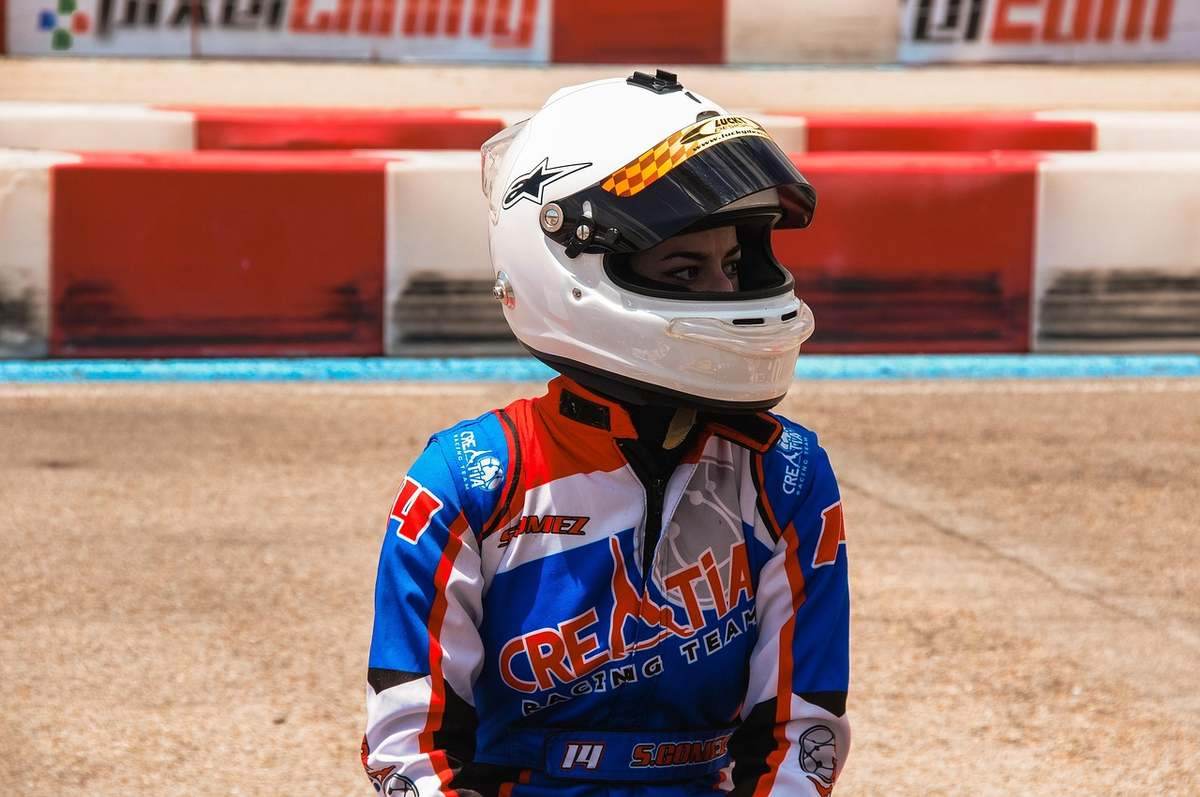 Pilote de course en combinaison bleue et rouge, portant un casque blanc, sur une piste de course Pilote de course en combinaison bleue et rouge, portant un casque blanc, sur une piste de course
