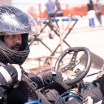 Un conducteur de kart en casque noir tient le volant sur circuit