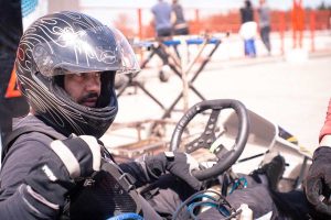 Un conducteur de kart en casque noir tient le volant sur circuit