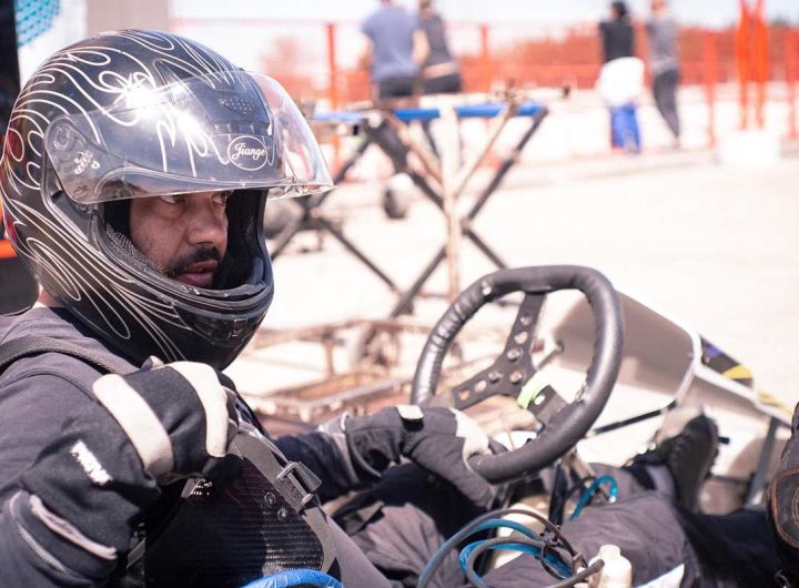 Un conducteur de kart en casque noir tient le volant sur circuit