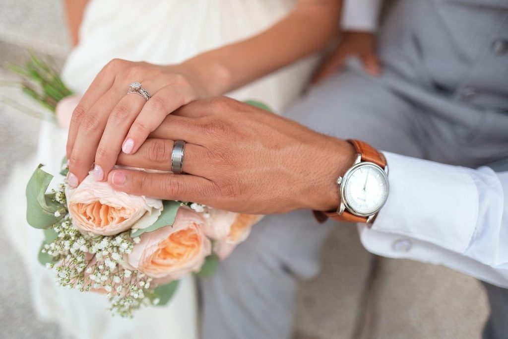 Mains tenant un bouquet, alliance et montre au poignet