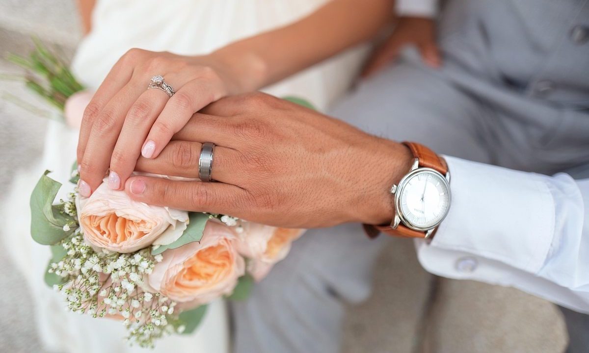 Mains tenant un bouquet, alliance et montre au poignet