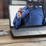 Laptop affichant une personne portant un stéthoscope, avec un stylo et un bloc-notes à proximité