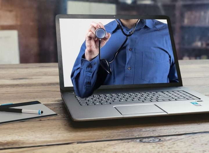 Laptop affichant une personne portant un stéthoscope, avec un stylo et un bloc-notes à proximité
