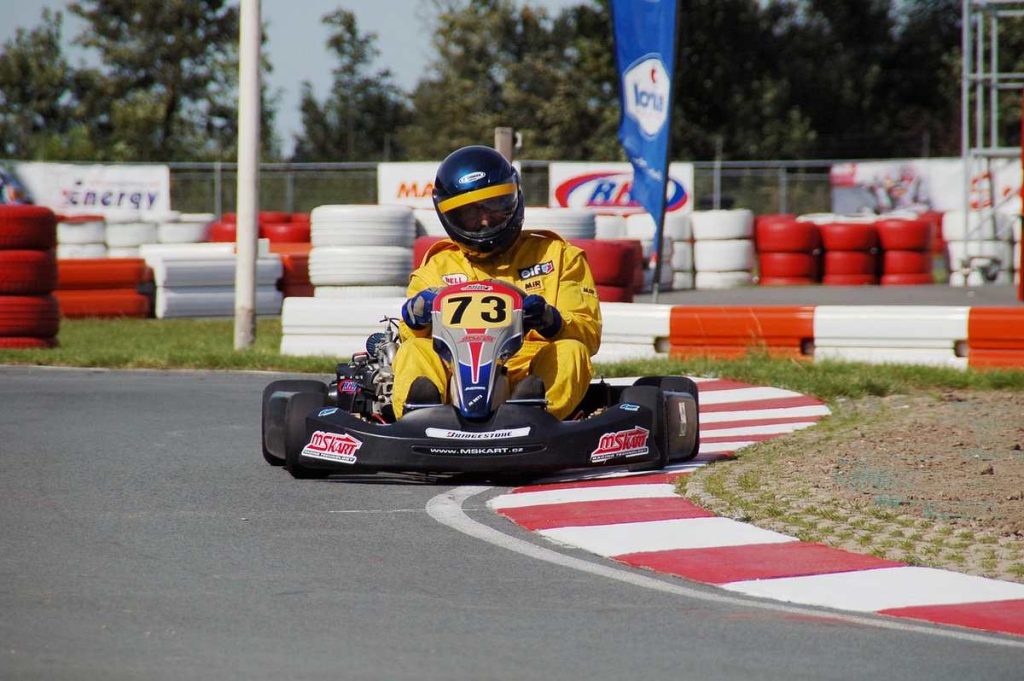 Un coureur en kart jaune 73 navigue sur virage de circuit