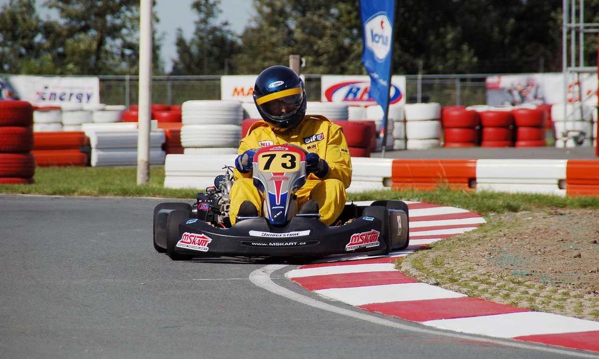 Un coureur en kart jaune 73 navigue sur virage de circuit