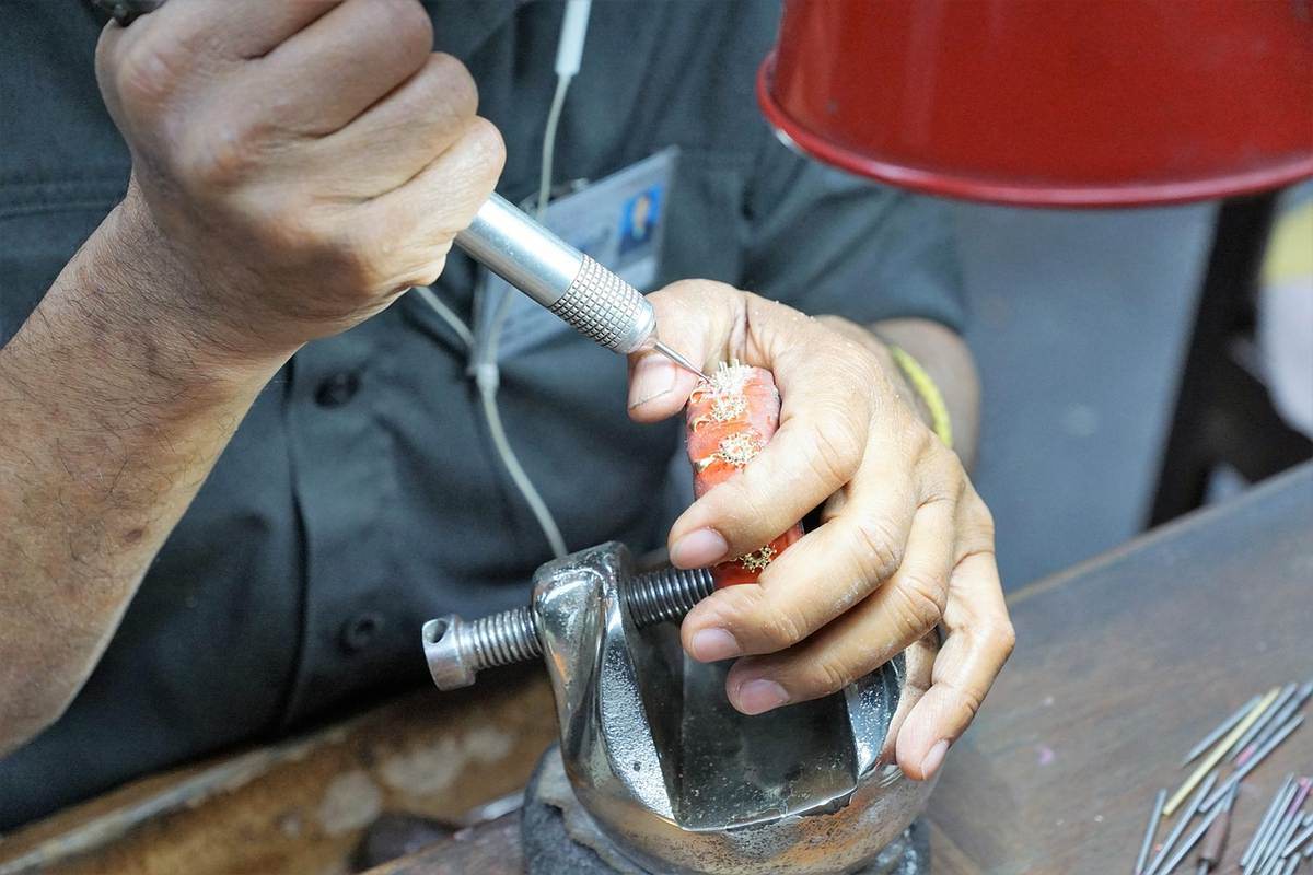 Person manipulant un objet rouge avec un outil électrique sur un établi